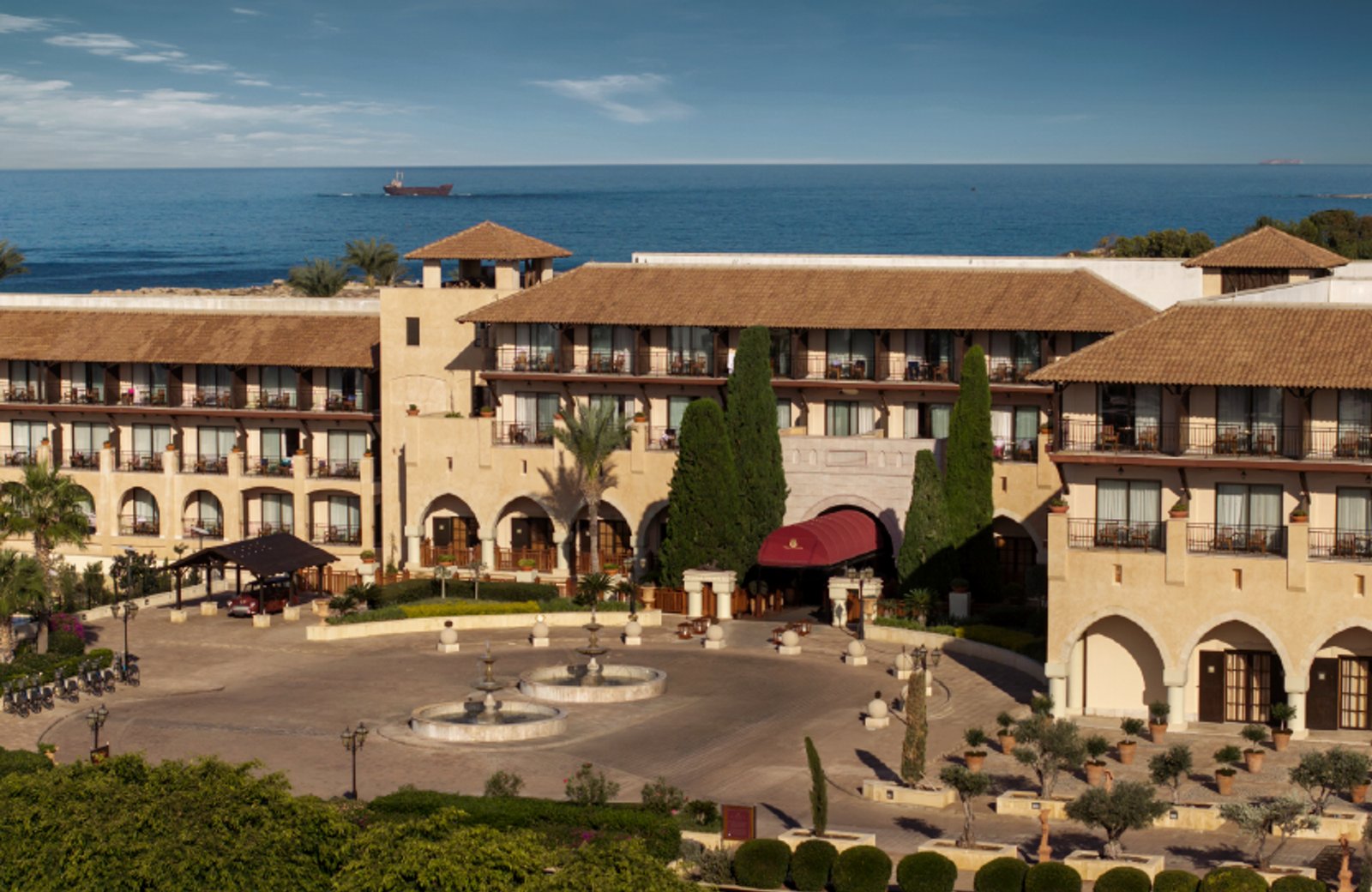 The palace-style Elysium Hotel above the sea in Kato Paphos, Cyprus, with a fountain courtyard in front.