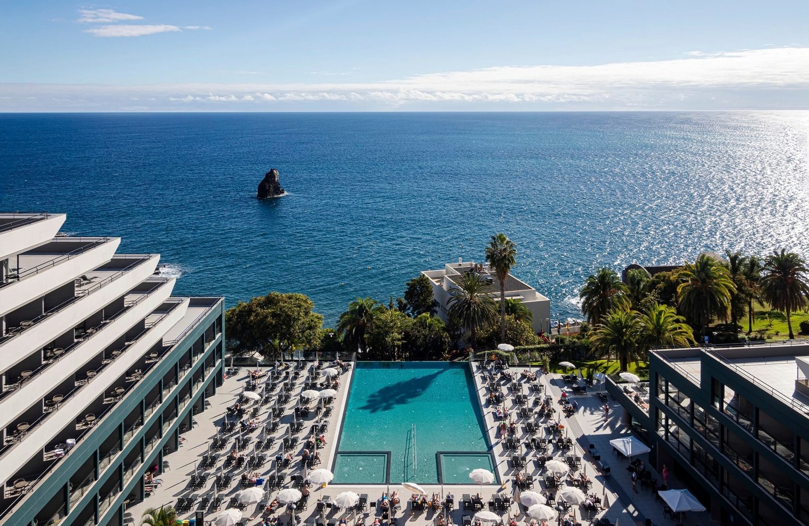 Enotel Lido, a modern hotel block above the sea on the Lido seafront in Funchal, Madeira, with an ocean-view pool terrace.