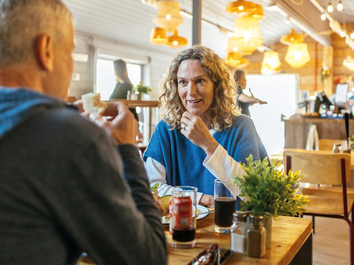 A timber-lined cafe interior with warm pendant lights and a couple eating at a wooden table