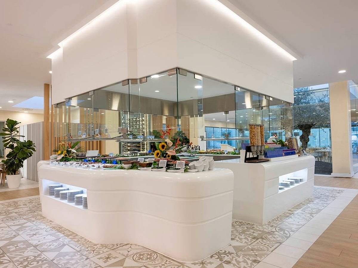 A curved white buffet island laid with salads, breads and flowers under a bright, high ceiling at Chaboco.