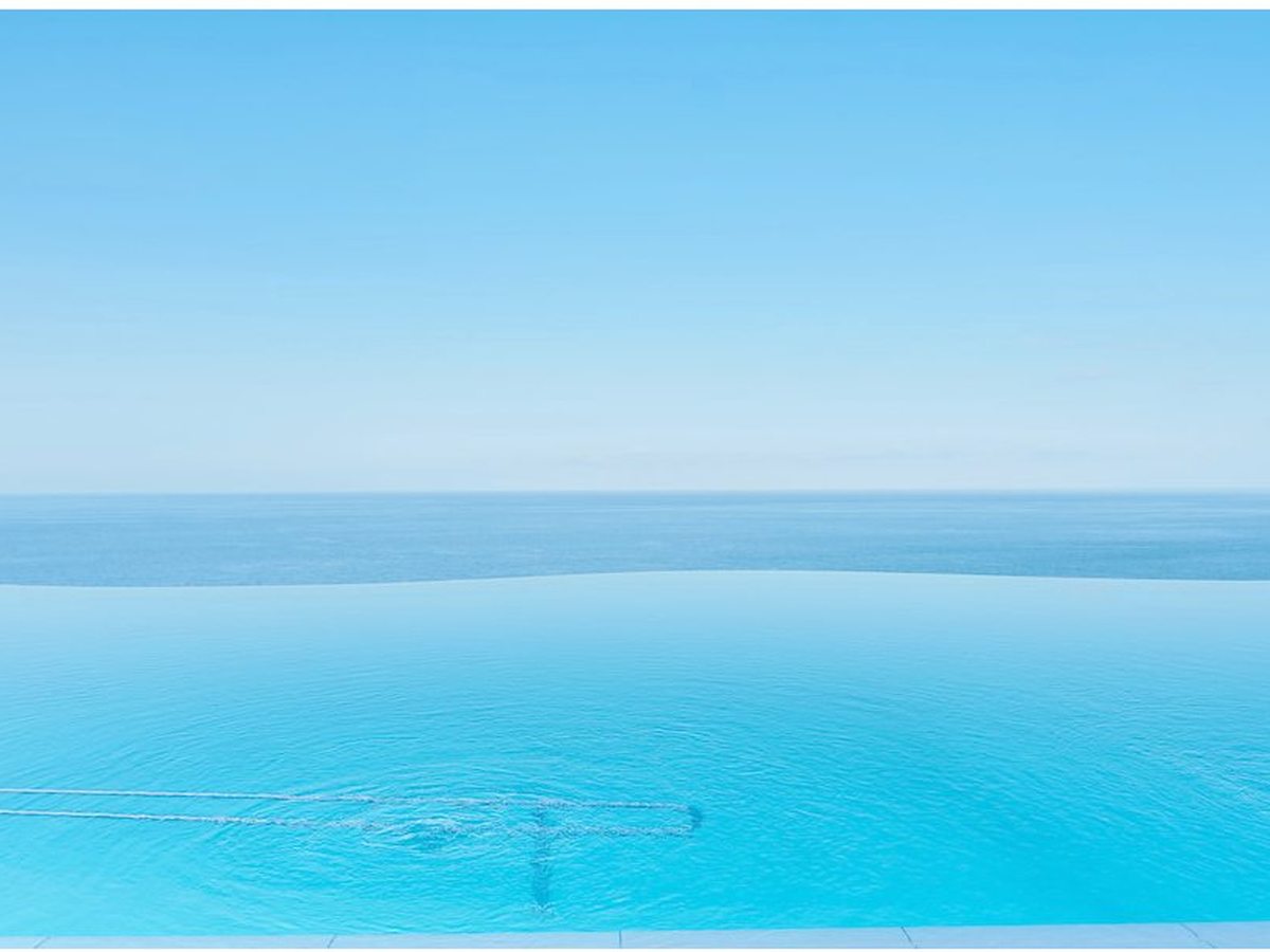 Infinity pool with its edge blending into the blue of the Atlantic under a clear sky.