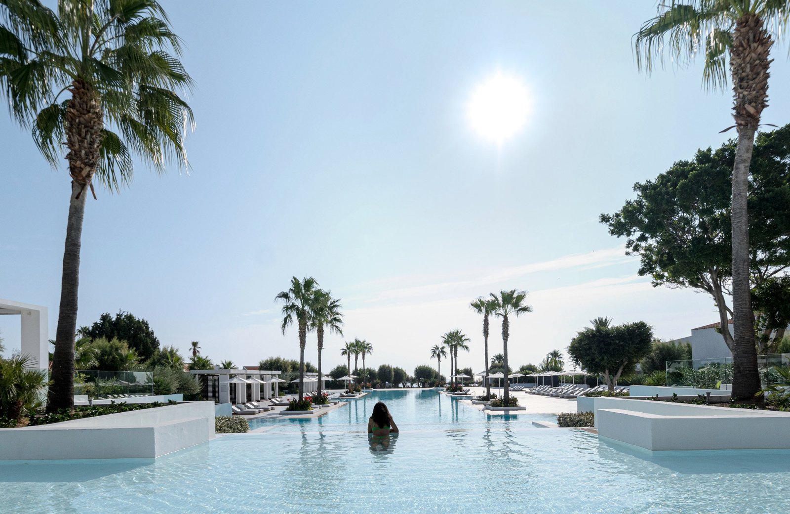 Grecotel LUX ME Dama Dama on Faliraki beach, Rhodes: low resort buildings and gardens behind a long pool, with the sand and the Aegean beyond.