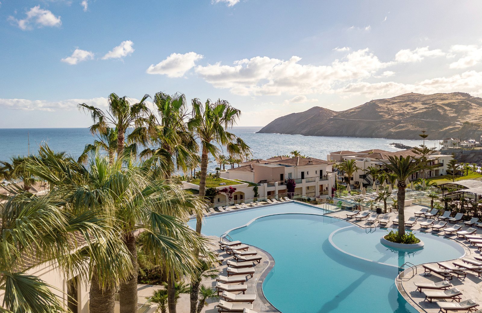 Grecotel Marine Palace & Aqua Park: low village-style buildings and pools set around a sandy bay at Panormos on the north coast of Crete.