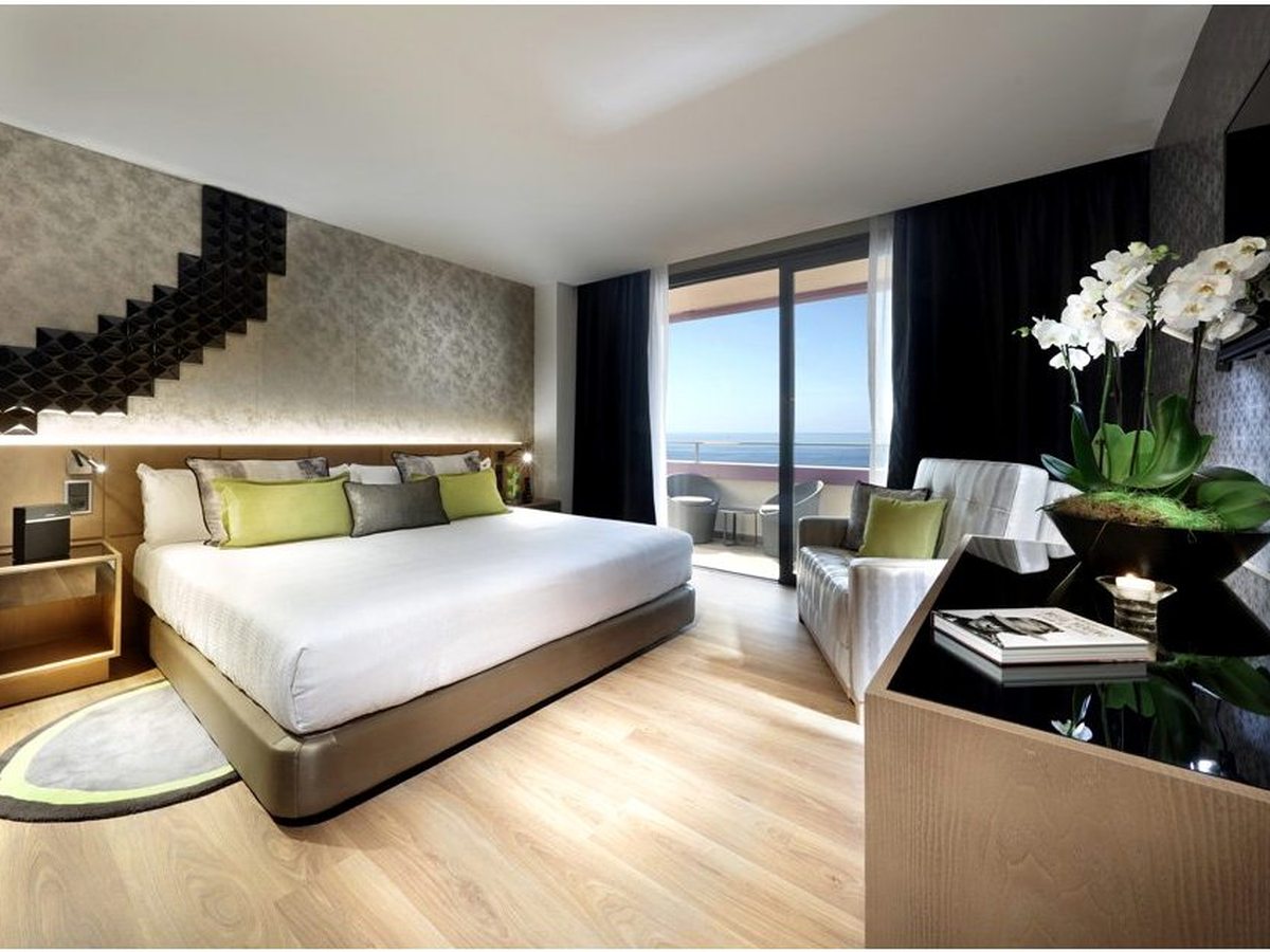 Bedroom with a king bed and a feature wall, balcony doors open to a full ocean view.