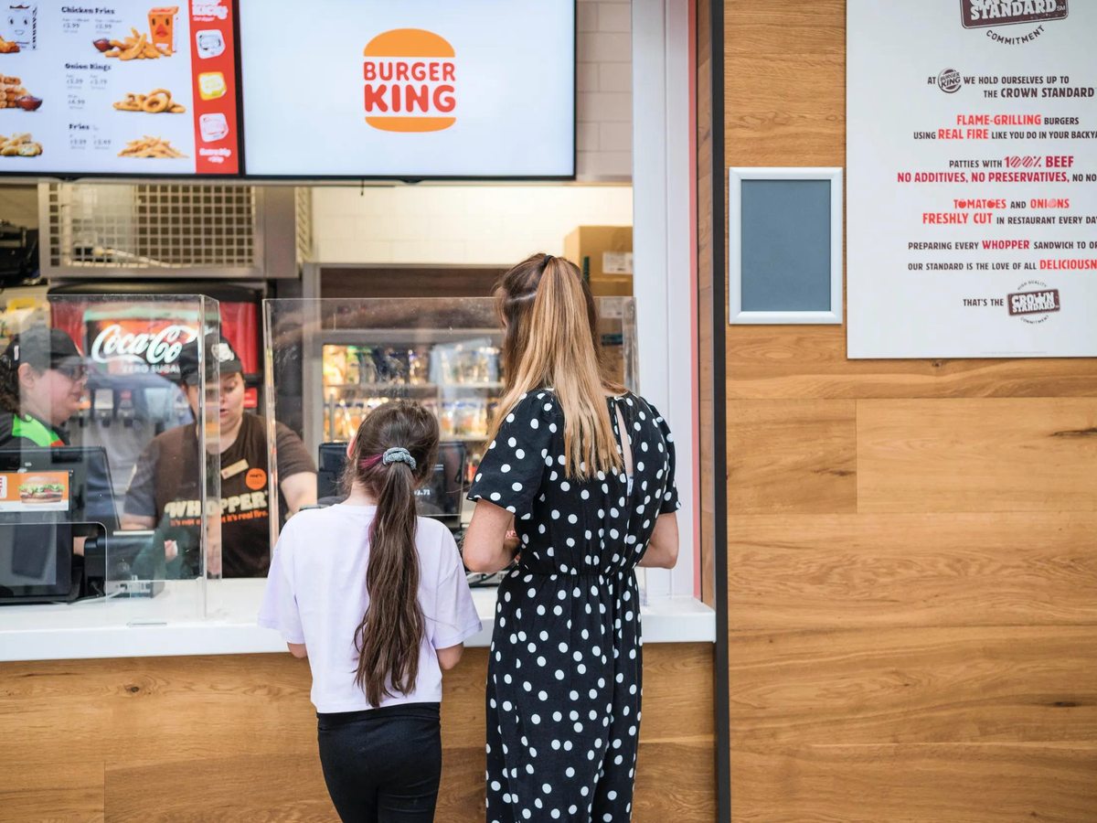 Guests ordering at the Burger King counter, illuminated menu boards overhead.