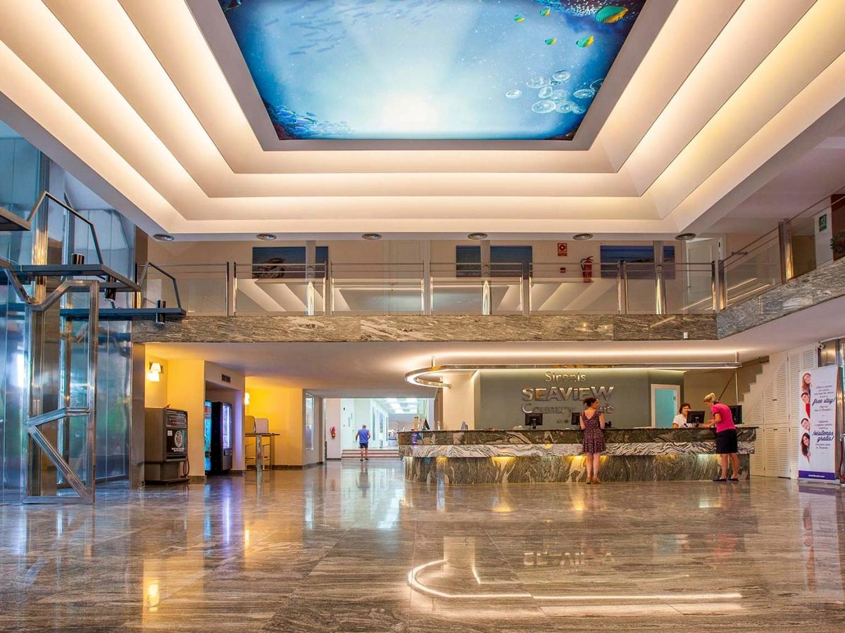 The lobby with a glass lift, a marble reception desk beneath a Seaview Country Club sign and an illuminated underwater-themed ceiling.