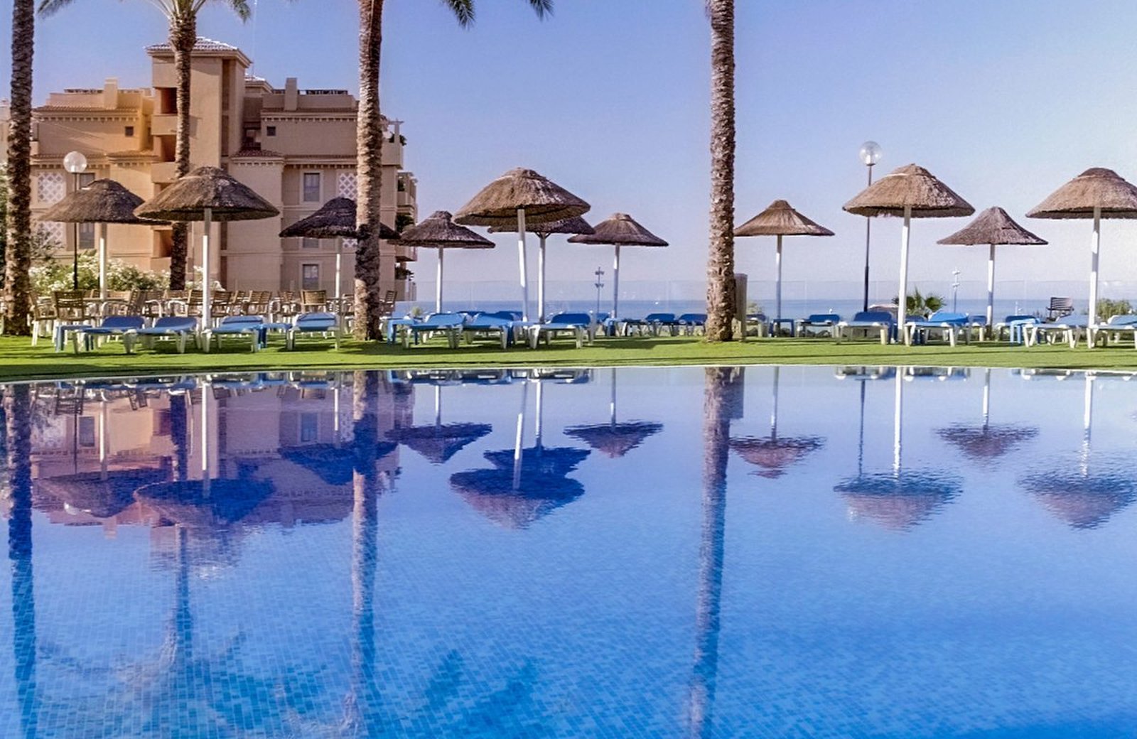 Hotel Holiday World Riwo at Benalmadena, its tropical-themed grounds and pool with the Costa del Sol coast beyond.