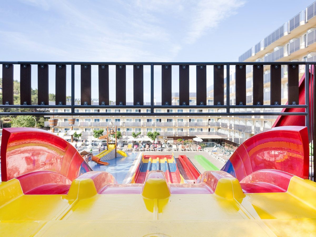 Multi-lane racing water slides in red and yellow running down into the splash pool.