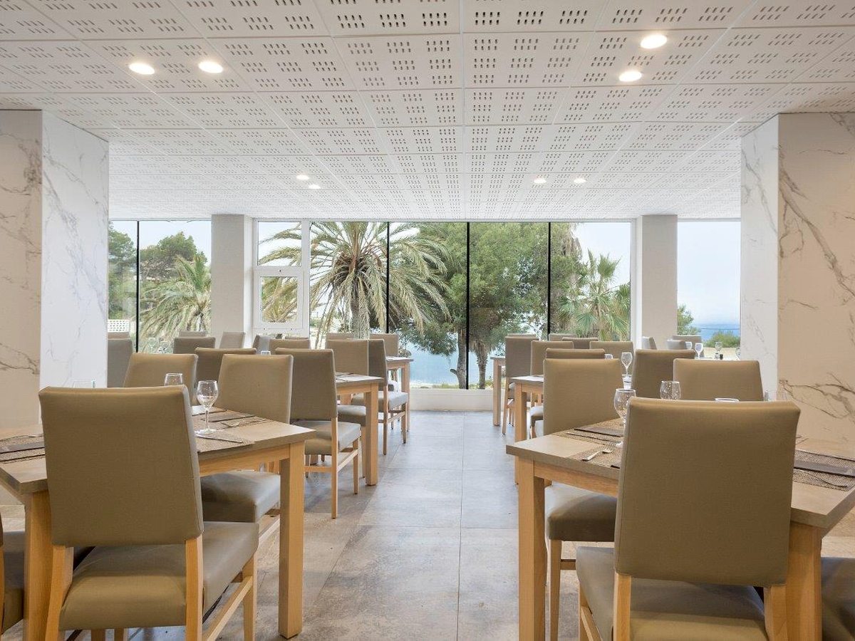 The buffet dining room with beige chairs and floor-to-ceiling windows onto greenery.