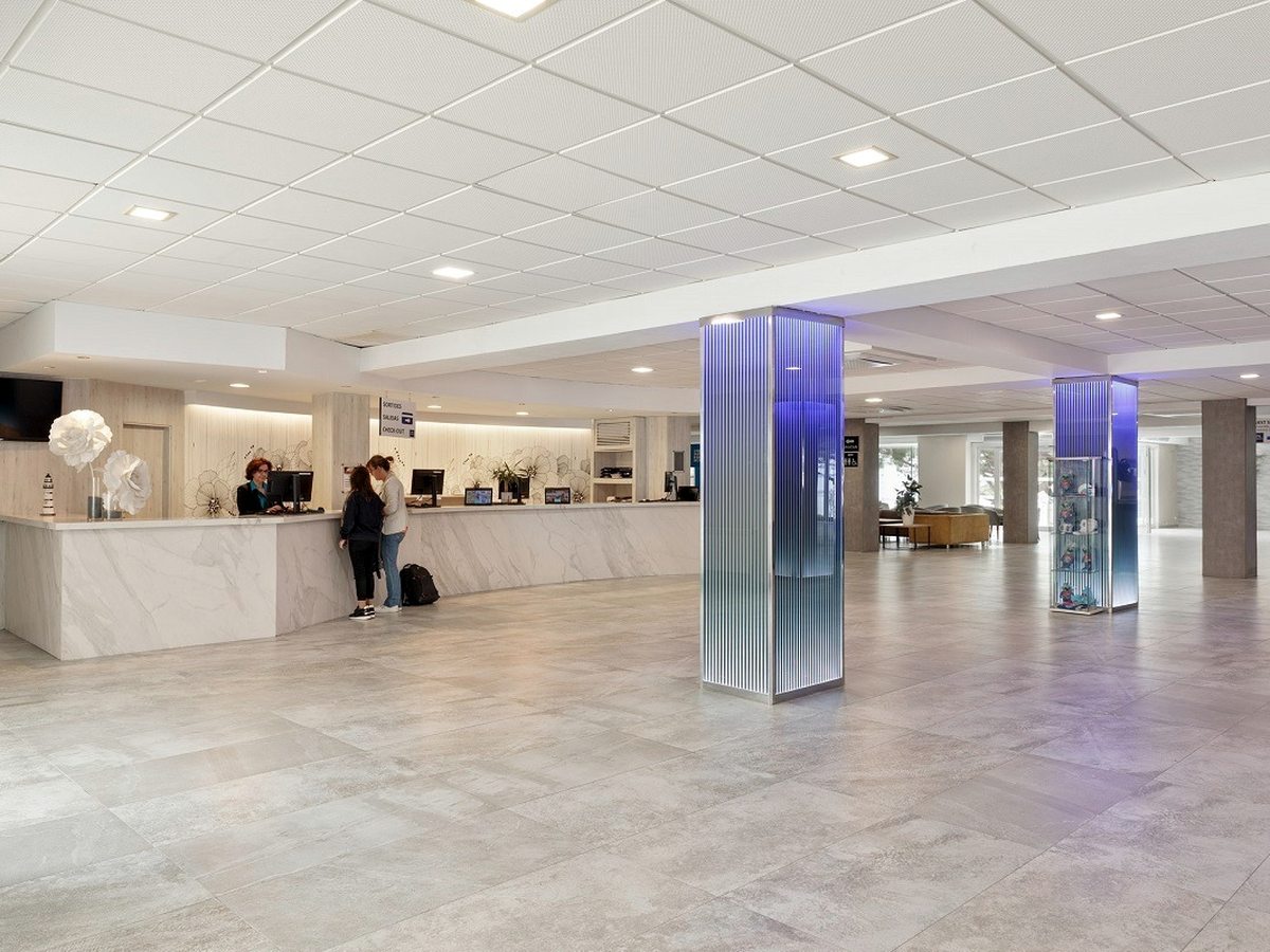 The bright, open reception hall with a polished floor and a guest arriving with luggage.