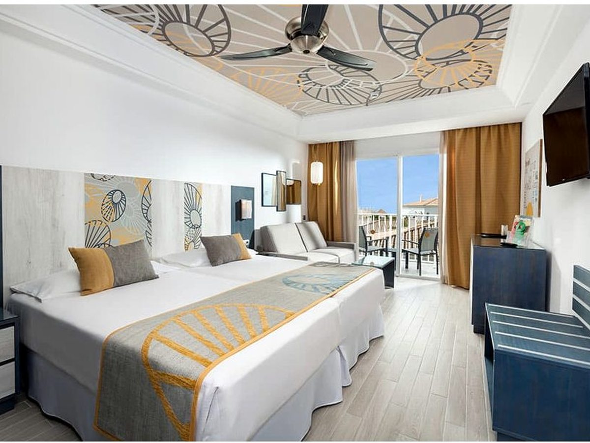 A double room laid out with two single beds, a sofa and a balcony looking over the resort.