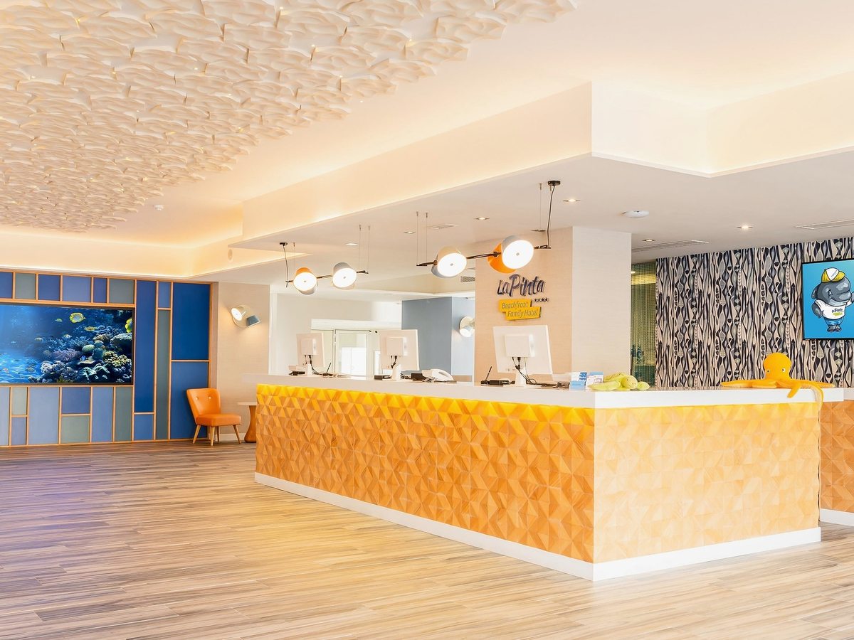A yellow-fronted reception desk in a bright lobby with blue marine-themed wall panels.
