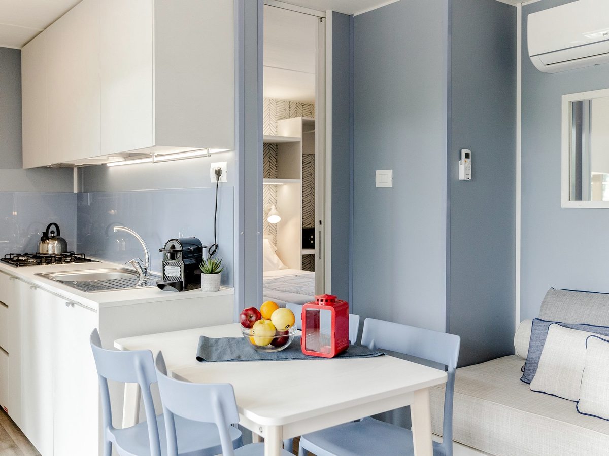 A compact fitted kitchen with a gas hob, sink and cupboards opening onto a dining area.