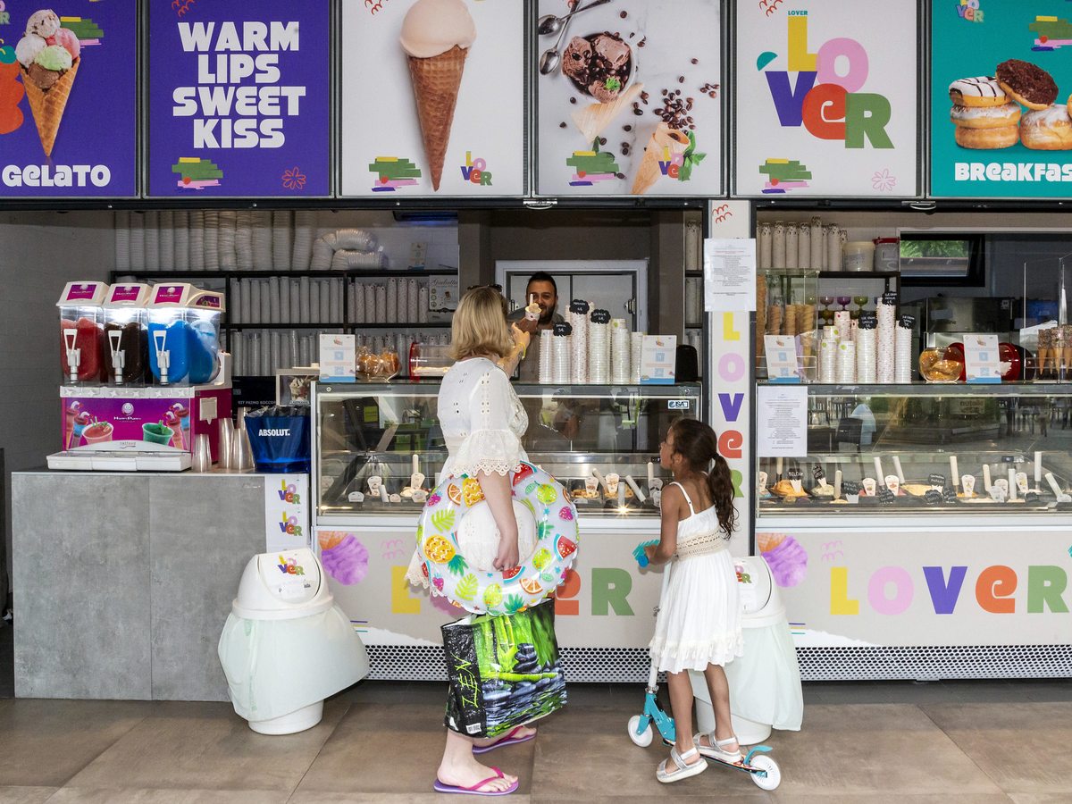 A child at the counter of a colourful ice cream kiosk signed Lover.
