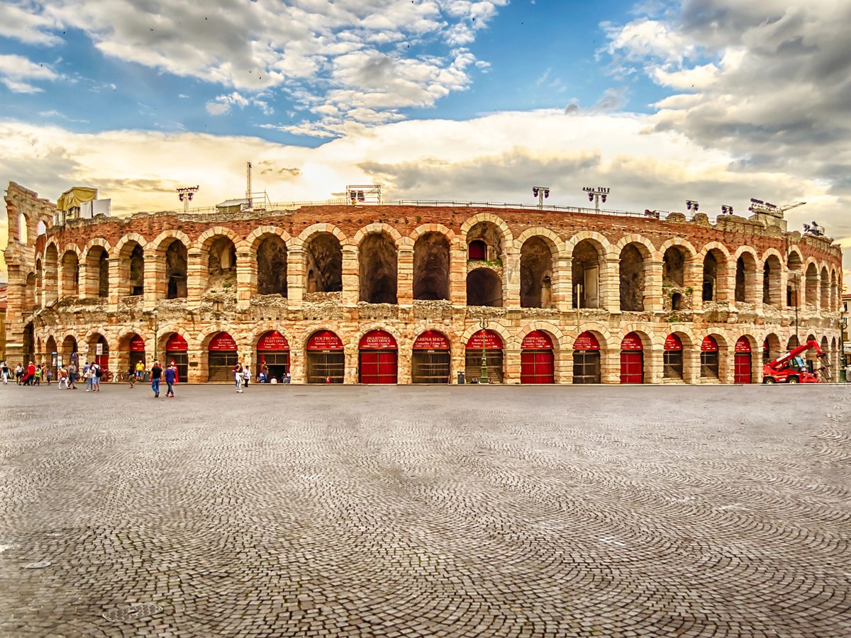The tiered stone arches of the Roman amphitheatre in Verona under a clear sky.