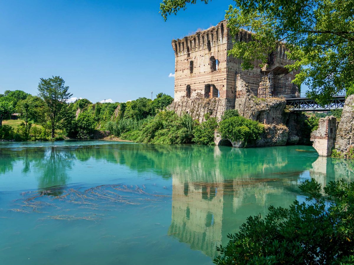 A stone bridge and an old tower beside the river at the watermill village of Borghetto sul Mincio.