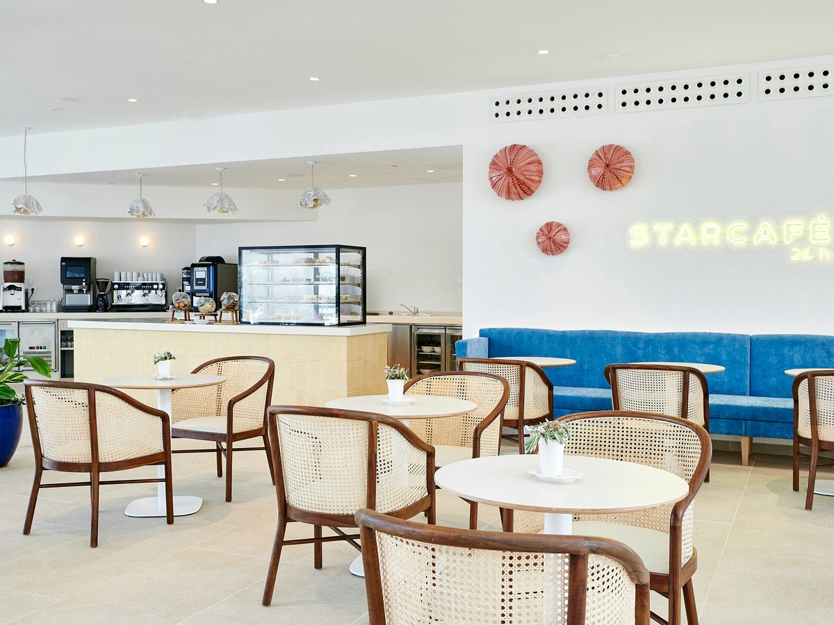 The Star Café counter with a coffee machine and pastry display, cane chairs and a blue banquette in a bright room.