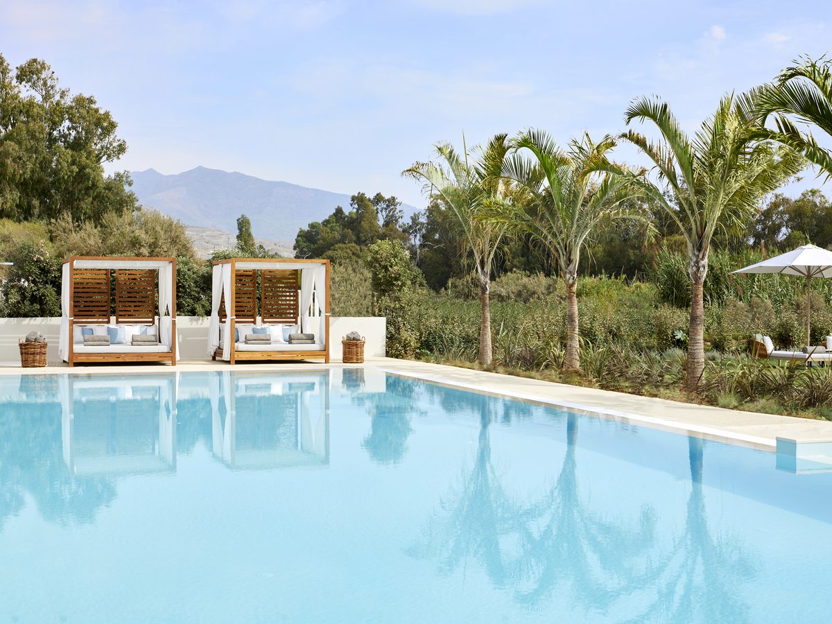 The adults-only pool at Ikos Andalusia, still water edged with loungers and clipped planting.