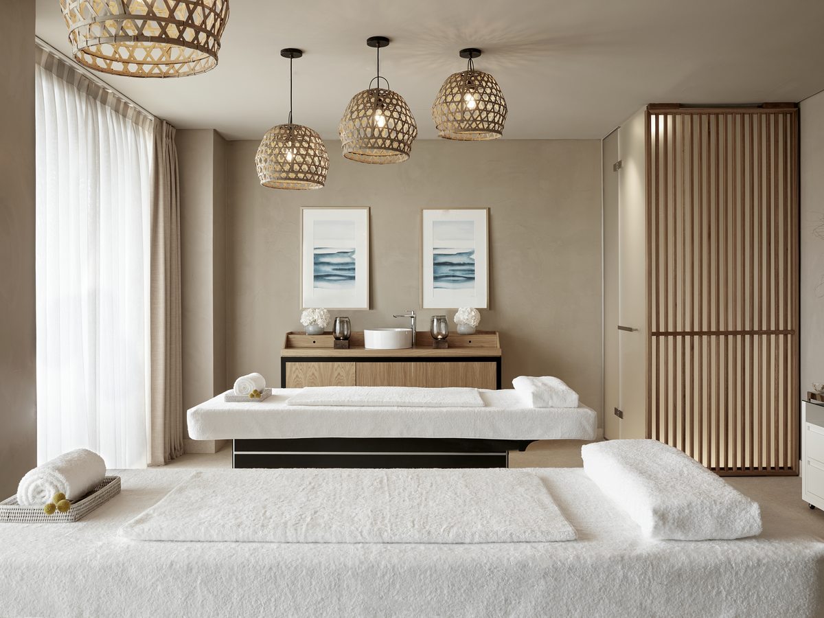 A treatment room in the spa at Ikos Andalusia, two massage beds with folded towels in calm neutral decor.