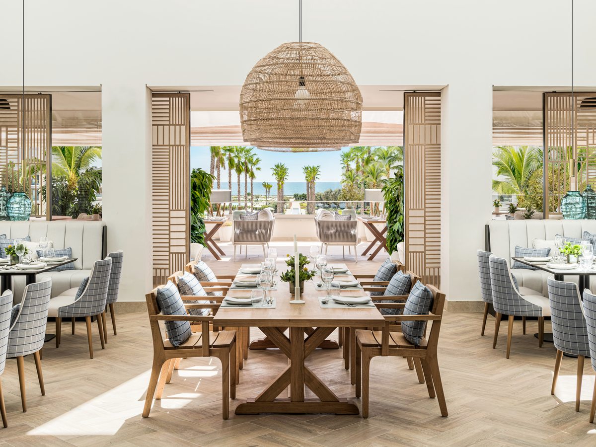 Flavors, the buffet restaurant at Ikos Andalusia, a long table and set tables in a bright dining room opening onto a terrace and the palm gardens.