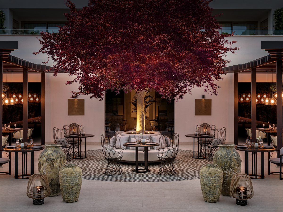 Anaya, the Asian restaurant at Ikos Andalusia, its courtyard terrace of dark tables under a red-leaved tree.