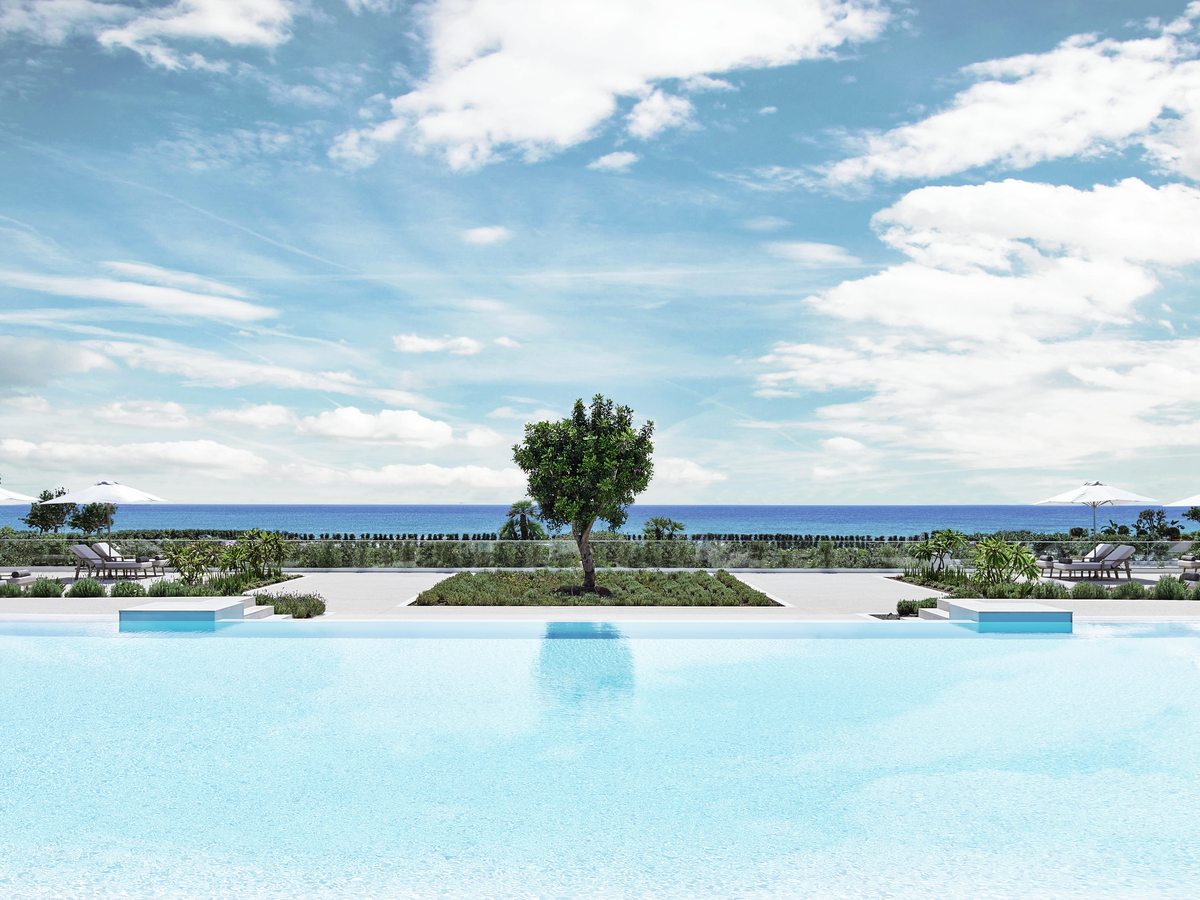 The main pool at Ikos Andalusia, a long rectangular pool with sunbeds and parasols around it and the Mediterranean beyond.