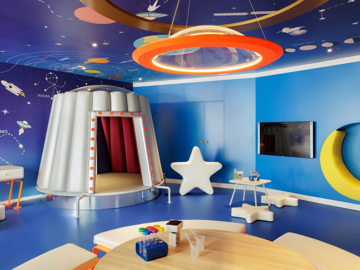 A space-themed activity room at the Heroes Village at Ikos Andalusia, with painted planets and low seating.