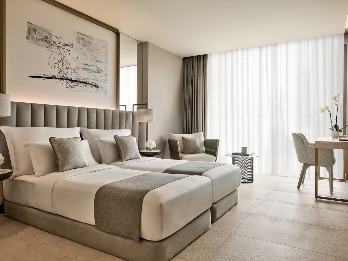 A Double Room at Ikos Andalusia, twin beds with a woven headboard in a pale neutral room.