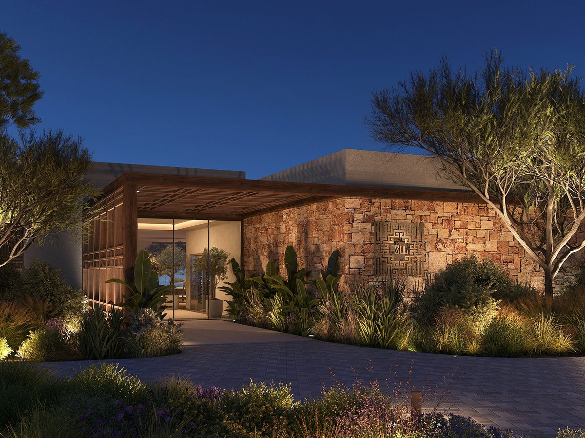The entrance to Azul at Ikos Kissamos, a stone-clad building with a timber pergola and planting lit up in the evening.