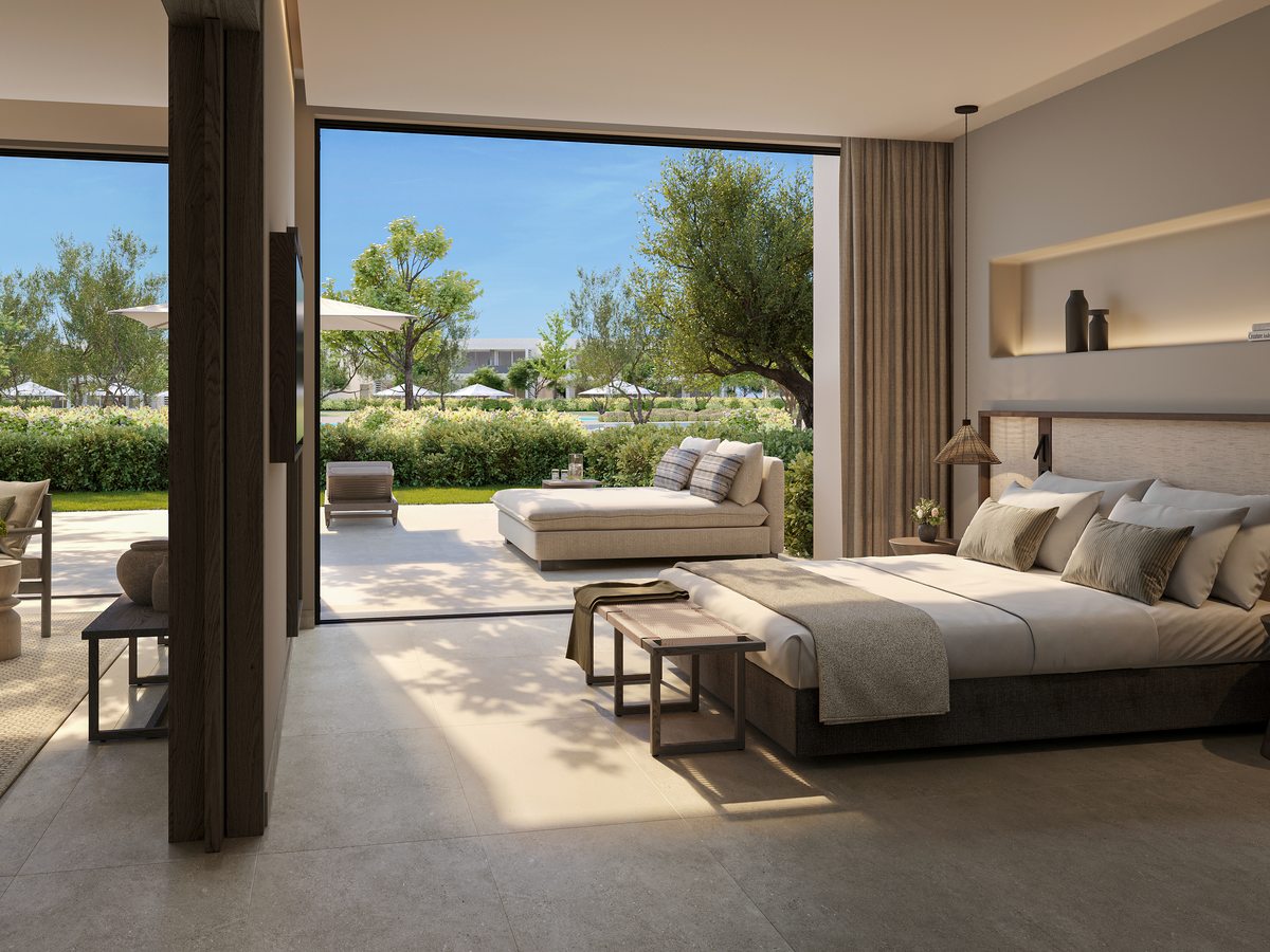 A One Bedroom Suite at Ikos Kissamos, its bed and daybed beside glass doors folded fully back onto a private garden terrace with loungers.