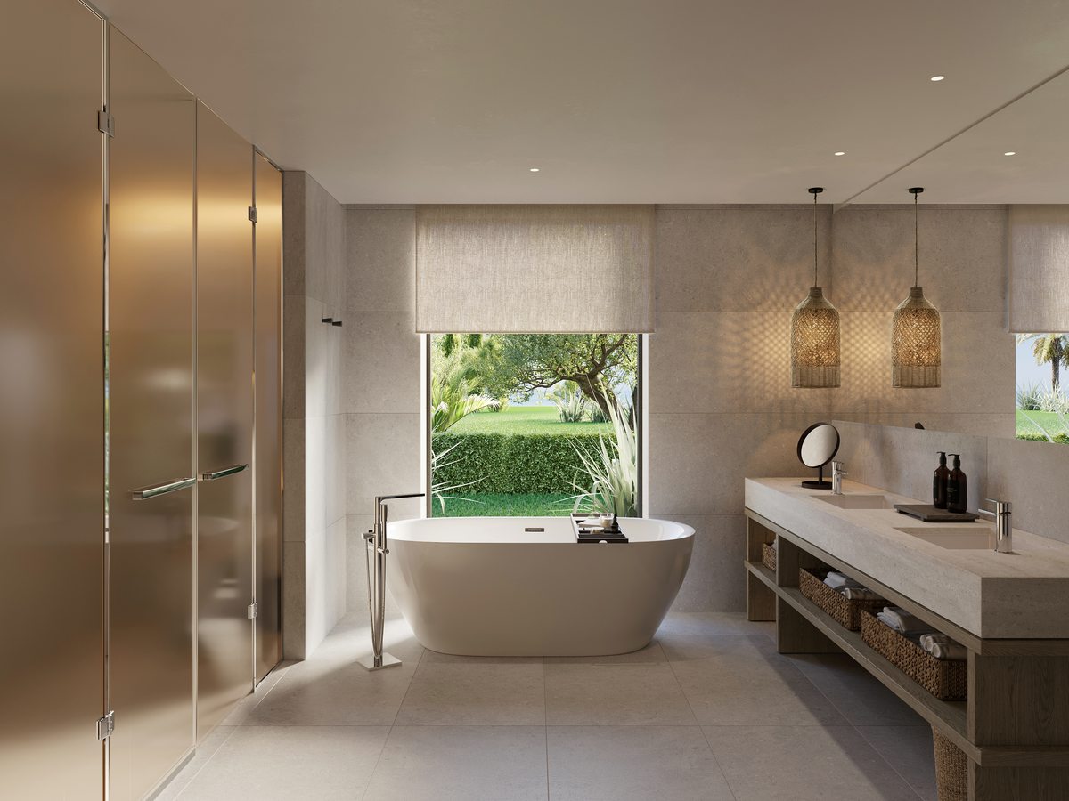 The bathroom of a Deluxe One Bedroom Suite at Ikos Kissamos, with a freestanding bath, a walk-in shower and a twin-basin vanity.
