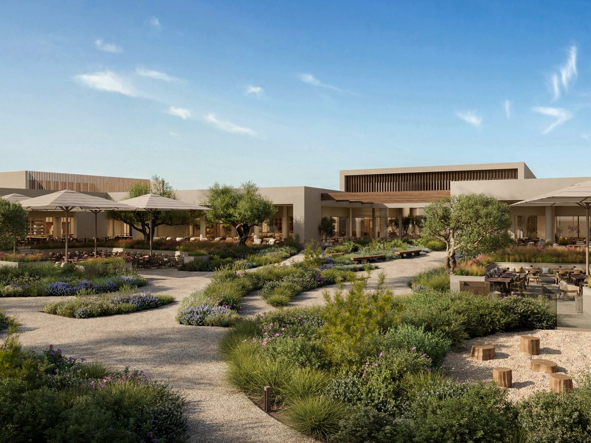 The central courtyard at Ikos Kissamos, with restaurant terraces and parasols around gravel paths and planted beds of olive trees and lavender.