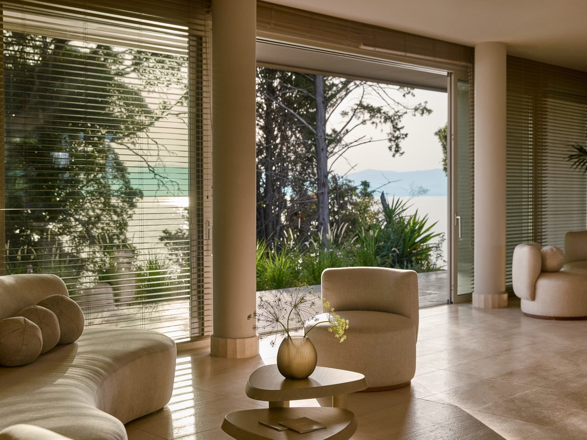 A relaxation room at the spa with low seating, soft lighting and tall windows onto the gardens.