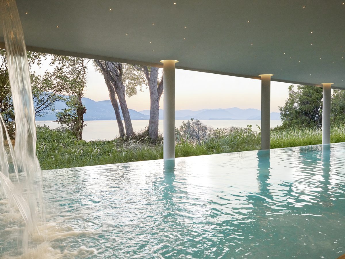 The indoor pool at the spa, running between tall columns to a full-height window onto the trees and the sea.