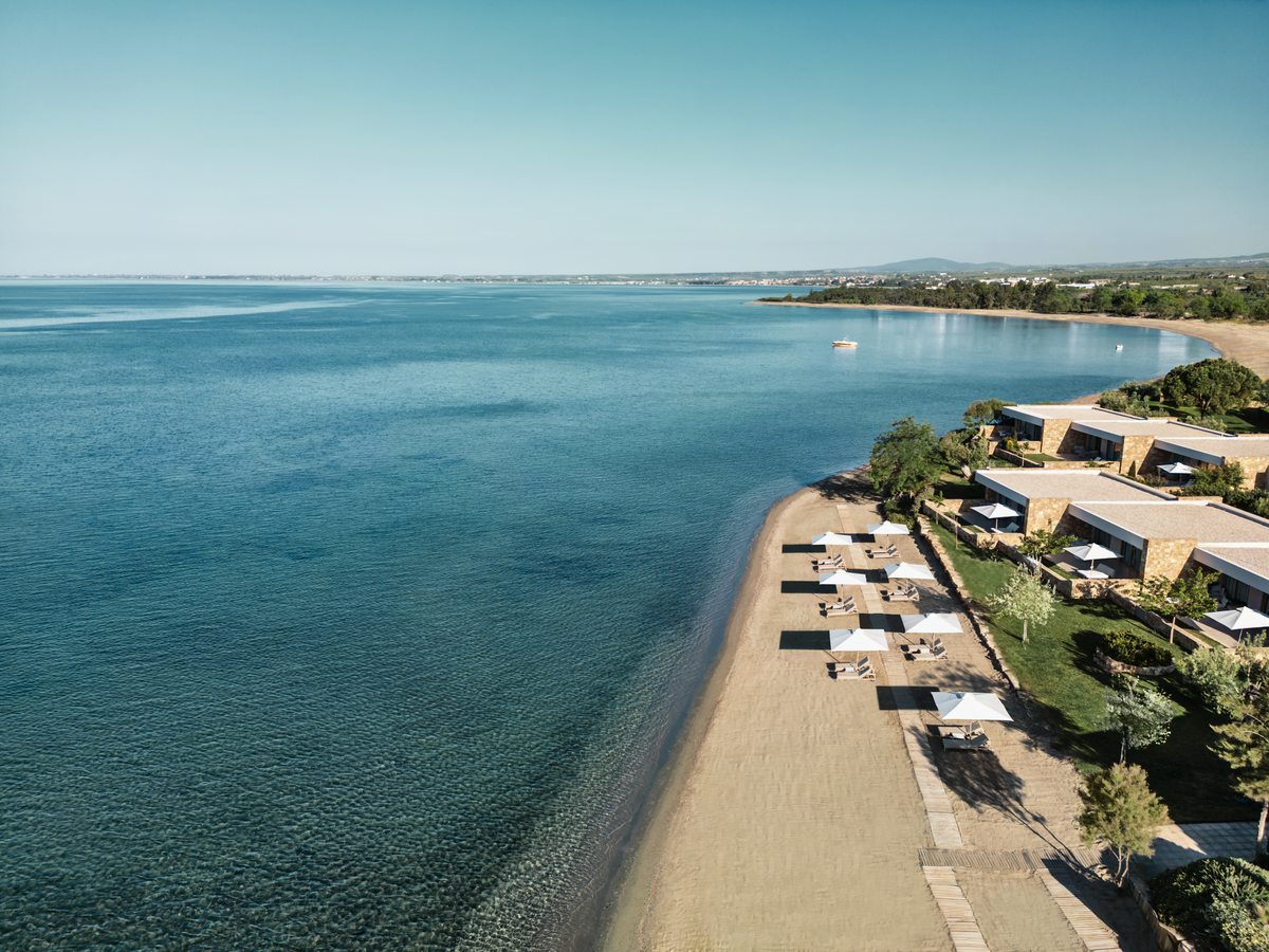 Ikos Olivia along the shoreline of the Gulf of Toroneos, its low buildings and beach running beside calm blue water.
