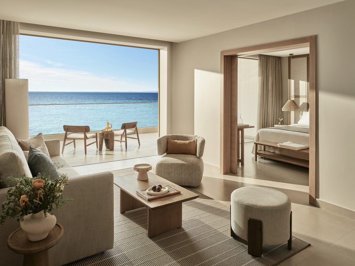 The living room of a Deluxe One Bedroom Bungalow Suite, with a sofa and armchairs facing an open terrace and the sea.