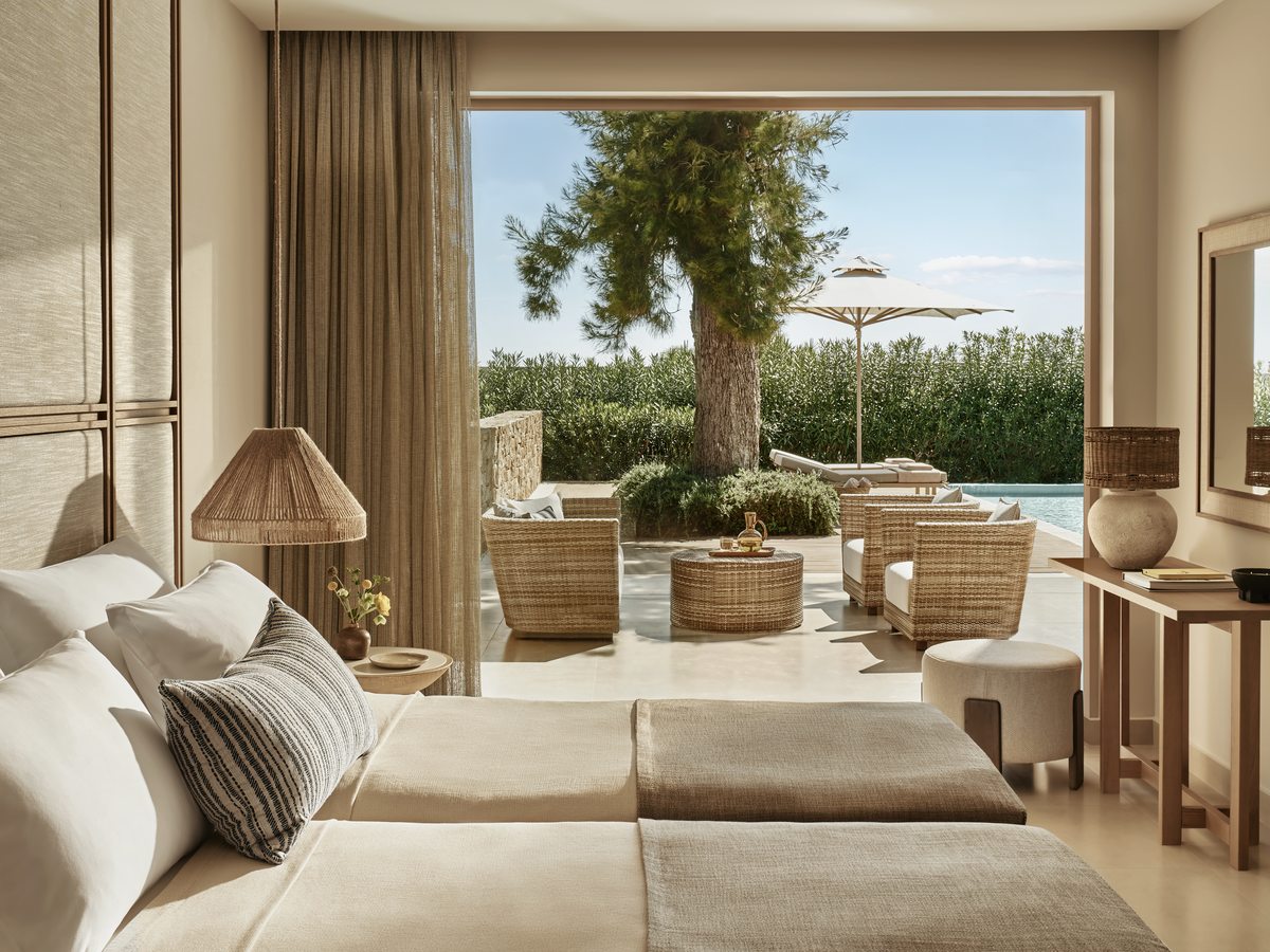 A bedroom in a Deluxe Two Bedroom Bungalow Suite, looking through sliding doors to a private pool terrace and a tree.