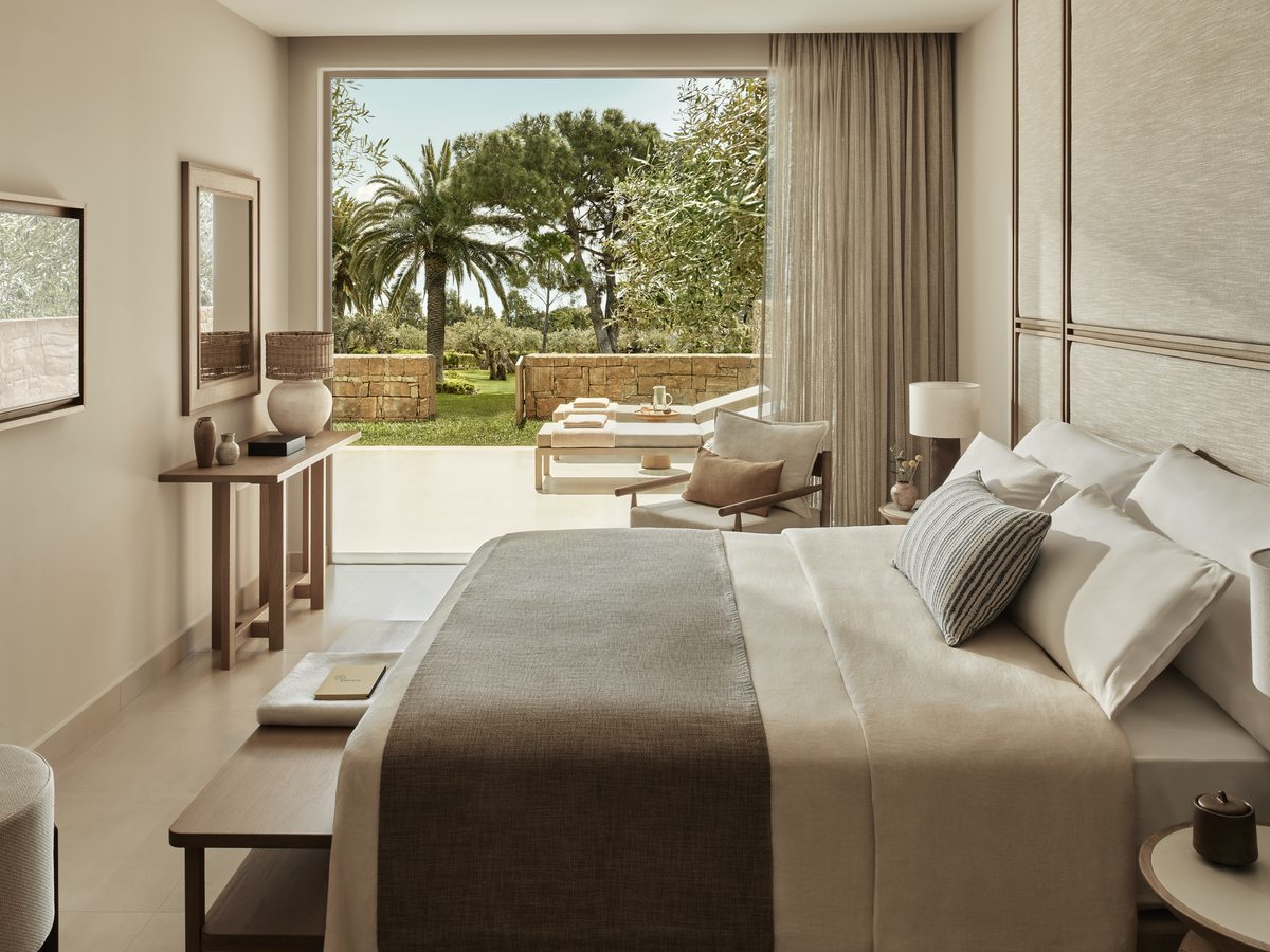 The bedroom of a One Bedroom Bungalow Suite, opening onto a private garden with loungers outside.