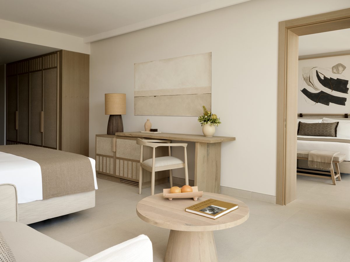 A Family Room with a bed, a writing desk and a long console, and a second sleeping area through an open doorway.