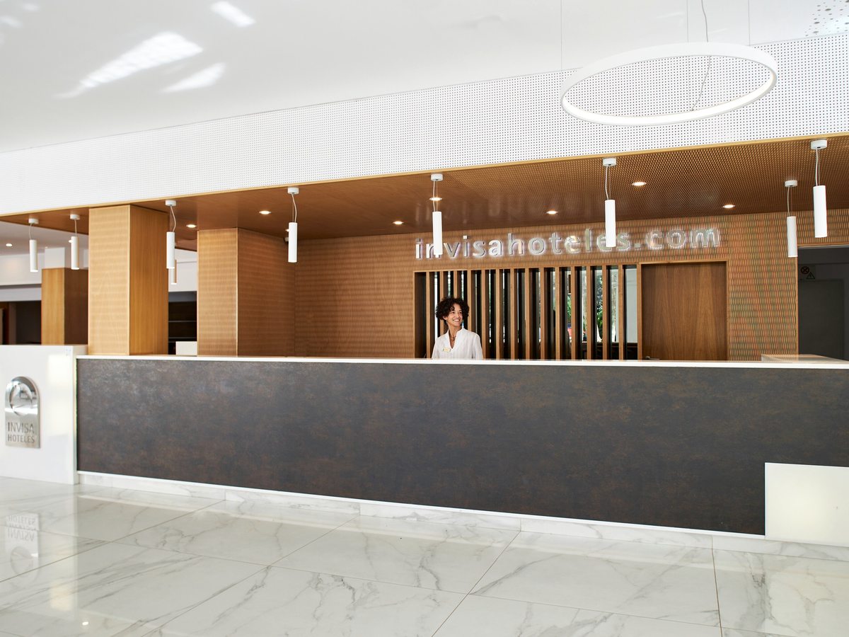 The hotel reception desk with a wood-panelled feature wall and a marble-effect floor.