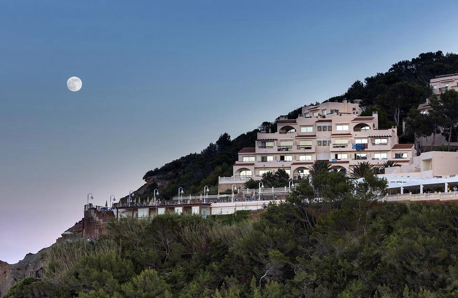 Invisa Figueral Resort above Playa Es Figueral, its two hotel buildings set on the cliff above a golden sandy beach and turquoise sea.