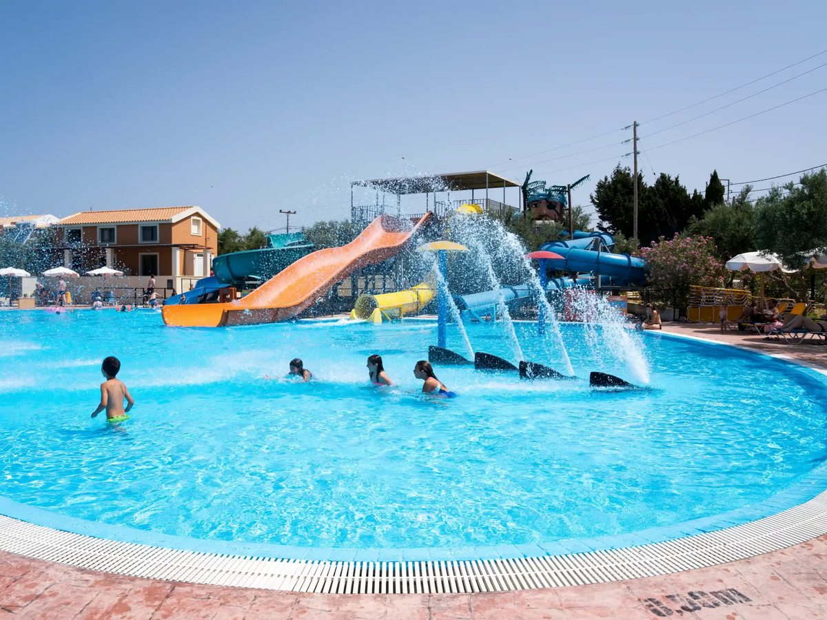 The aqua park pool with children in the water and a cluster of coloured water slides feeding into it.