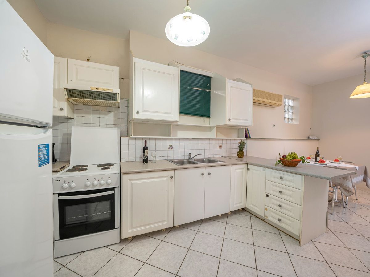 A self-catering kitchen with white cabinets, a full-size fridge-freezer, an oven, a hob and a sink.
