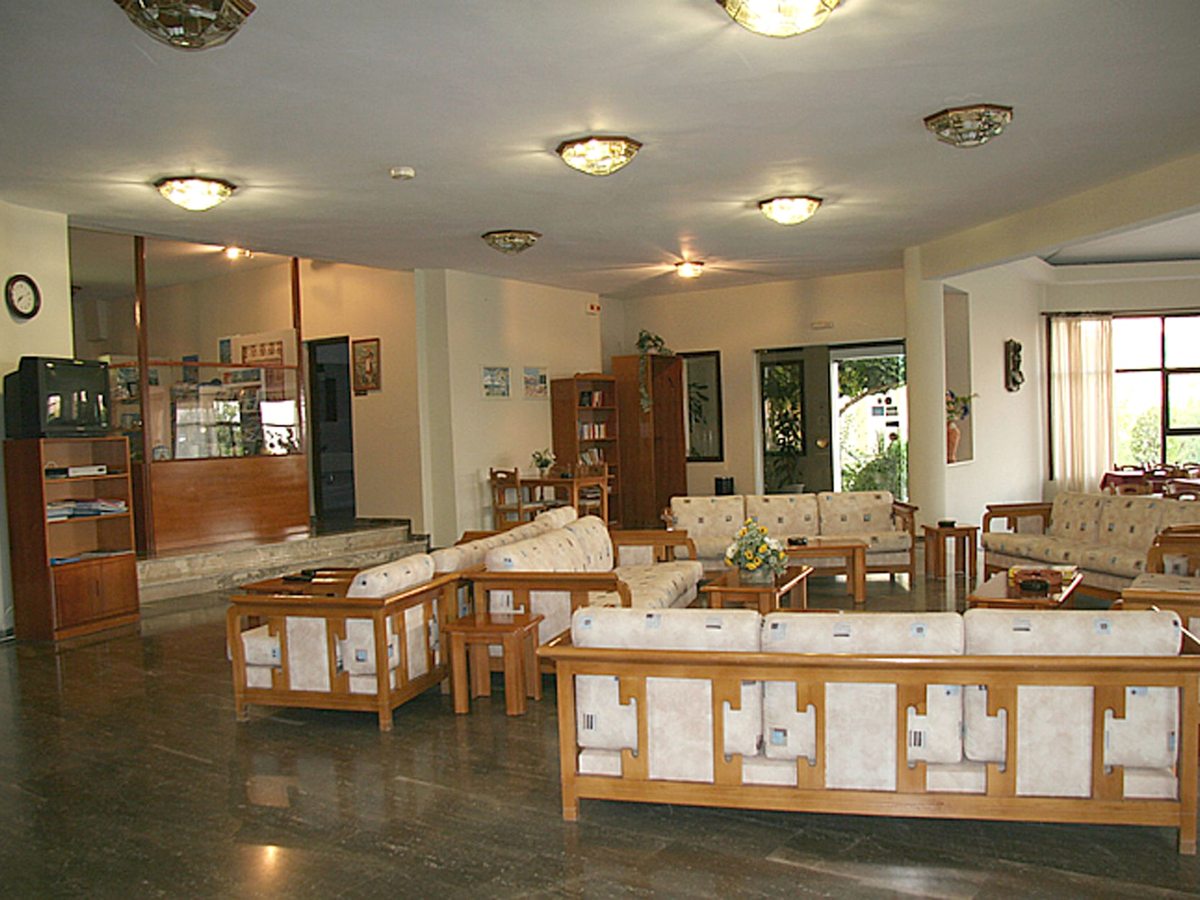 The hotel's indoor reception desk beside a lounge with wooden sofas and low tables.