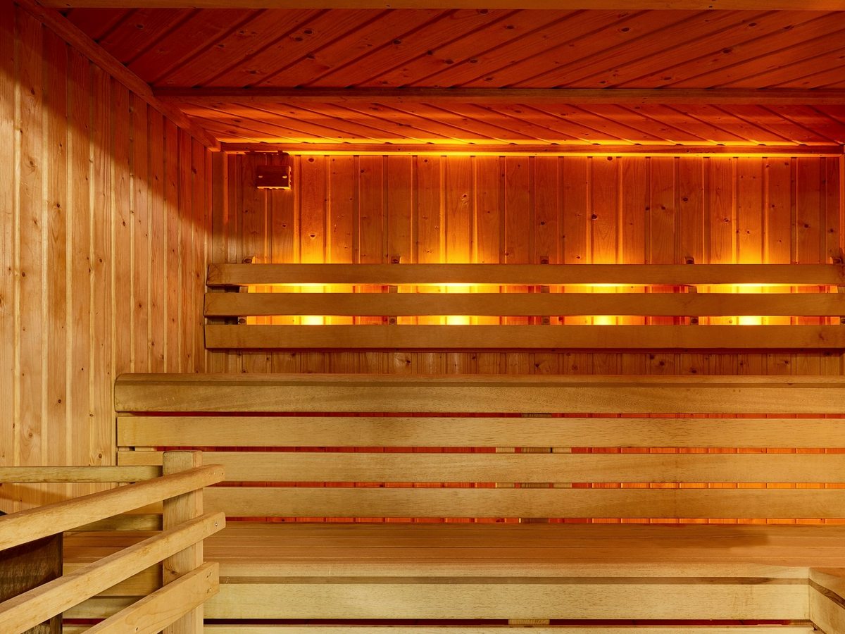 A pine-lined sauna with tiered benches and warm strip lighting under the top bench.
