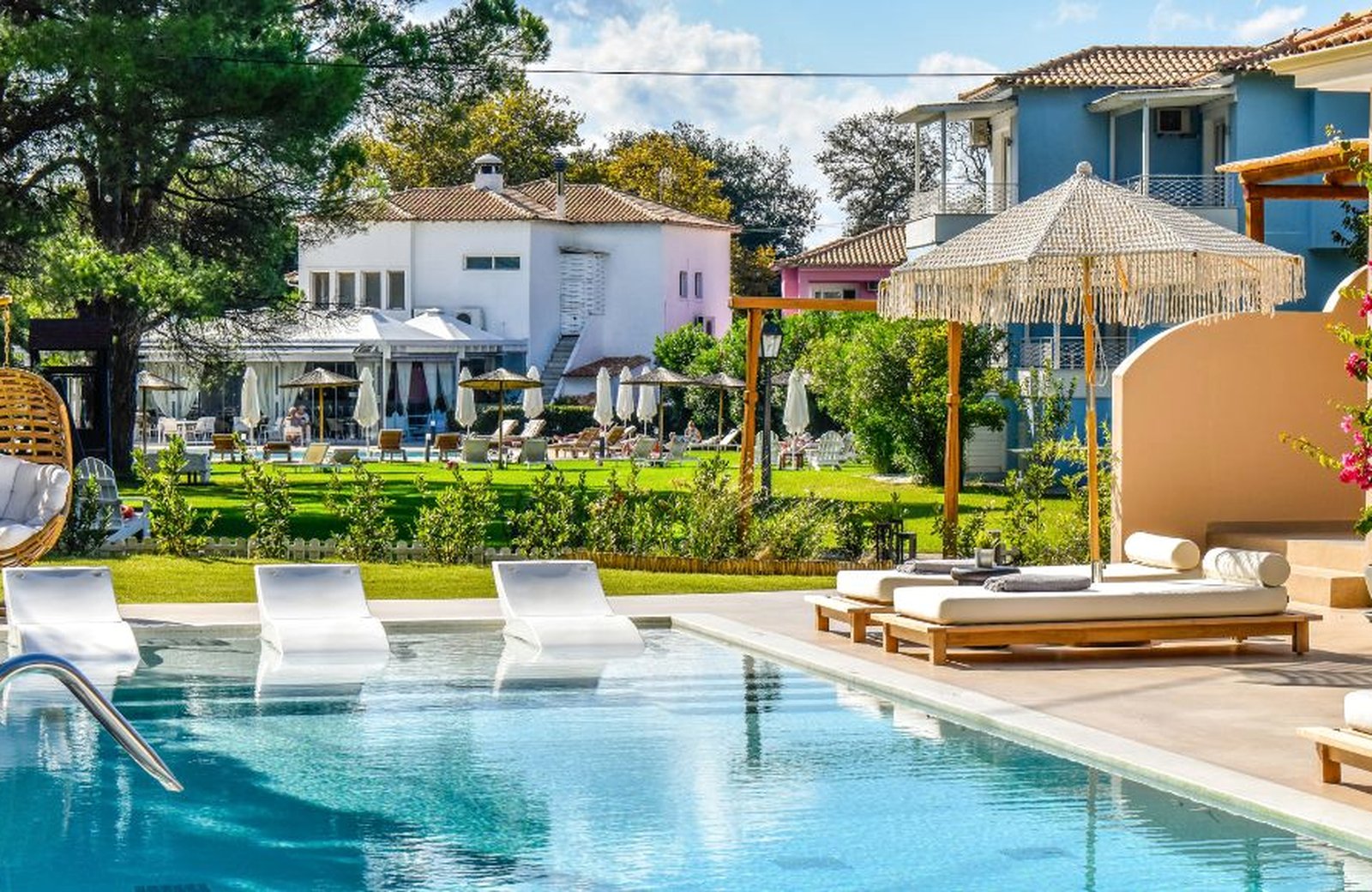 Mandraki Village Boutique Hotel: low pastel garden buildings around a pool, on flat ground by the Strofilia pine forest at Koukounaries.
