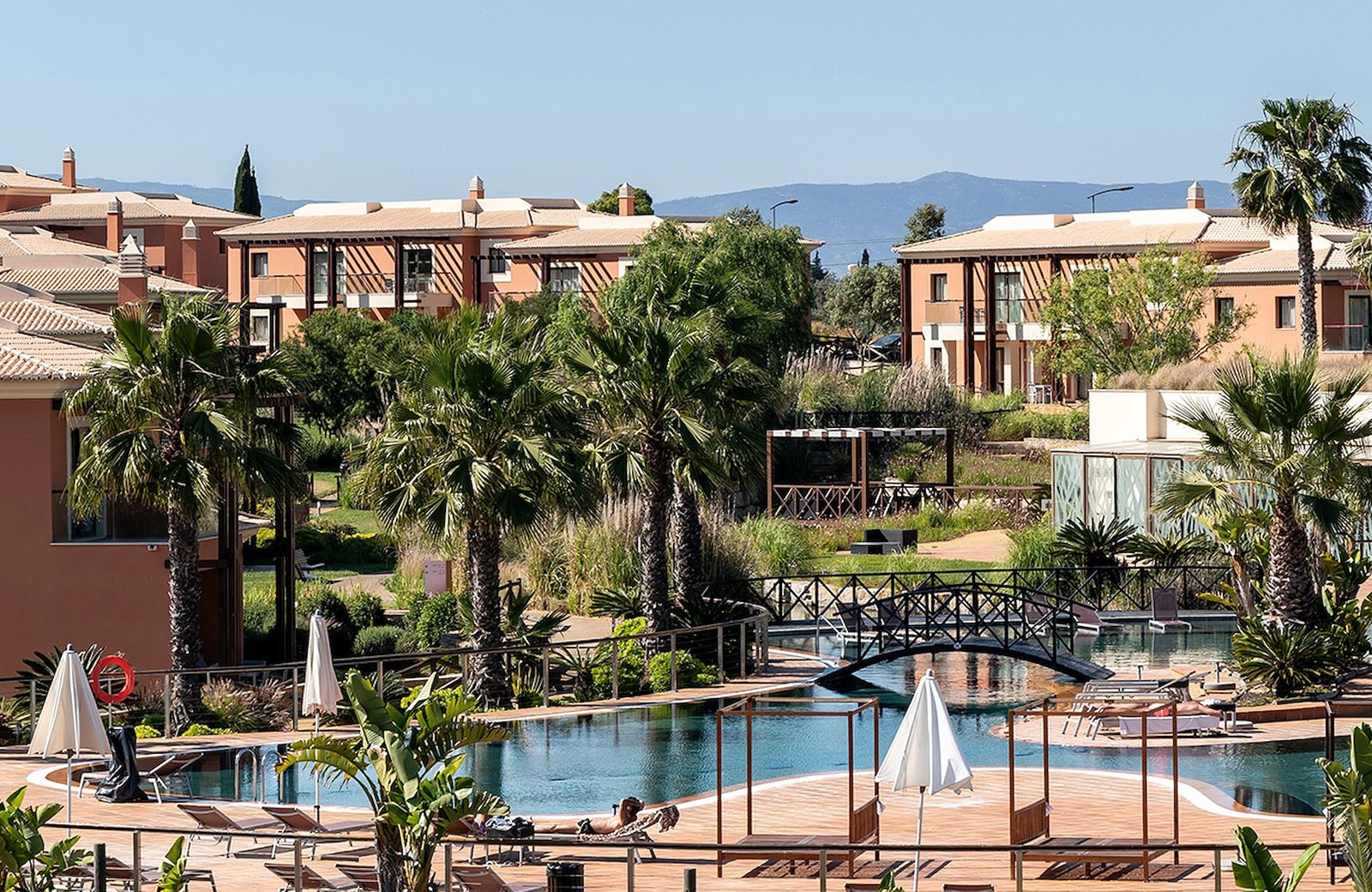 Monte Santo Resort above Carvoeiro in the Algarve: low-rise suites in earthy tones set among manicured gardens, lakes and a large pool.