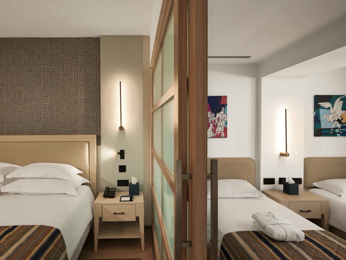 Double bed on one side of a timber-framed frosted sliding partition and two single beds with striped runners on the other.