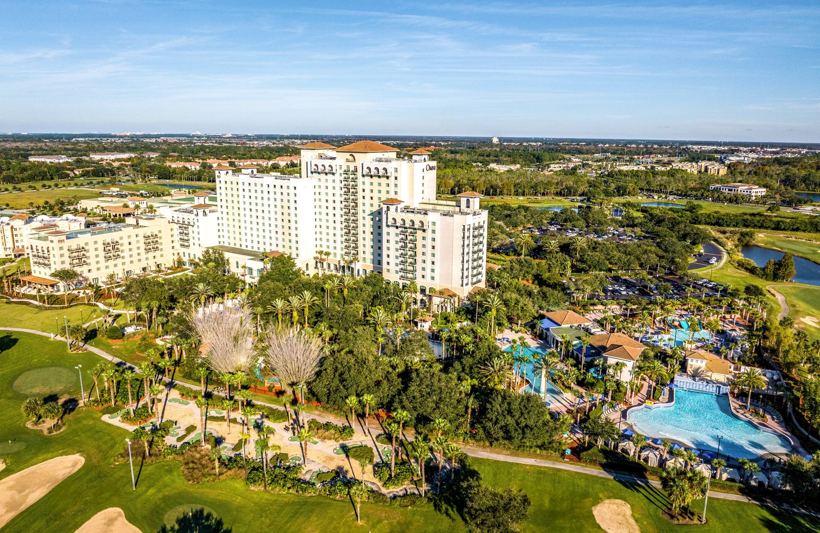 Omni Orlando Resort at ChampionsGate from the air: the resort tower and its pool complex set among the fairways, bunkers and lakes of the golf courses.