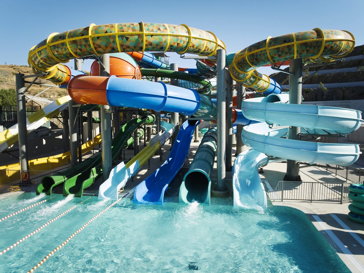 Tall waterpark tower of looping blue, green, orange and patterned slides ending in a splashdown pool with lane ropes.